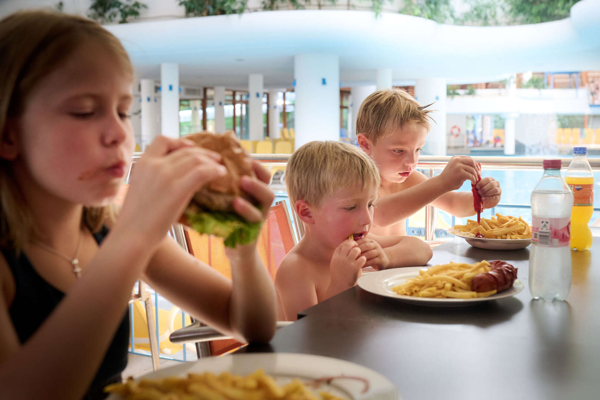 Kinder essen Pommes und Burger im Aquaria Bistro