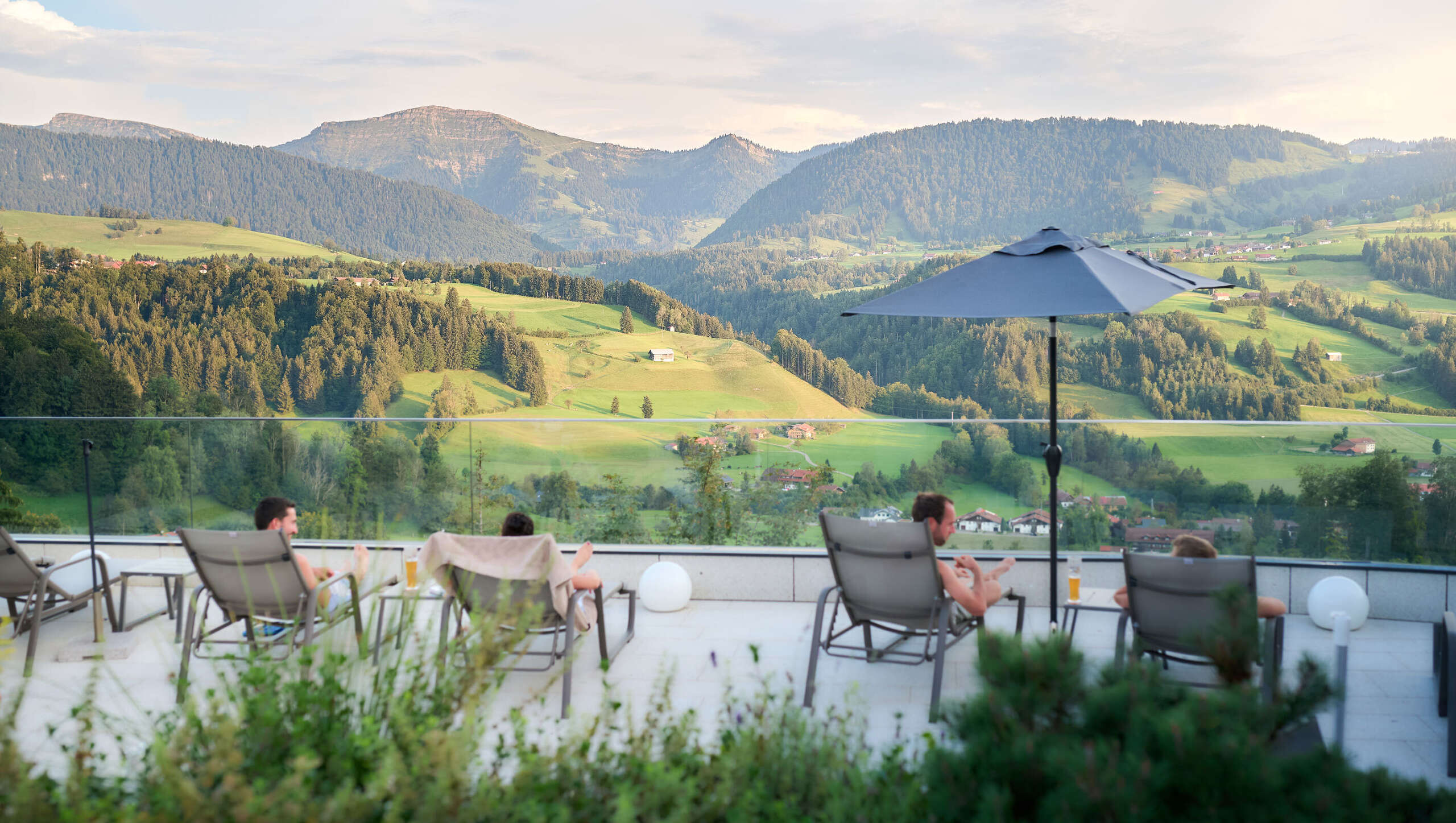 Entspannen auf den Liegen der Sonnenterrasse im Aquaria Außensaunabereich mit Bergpanorama im Sommer