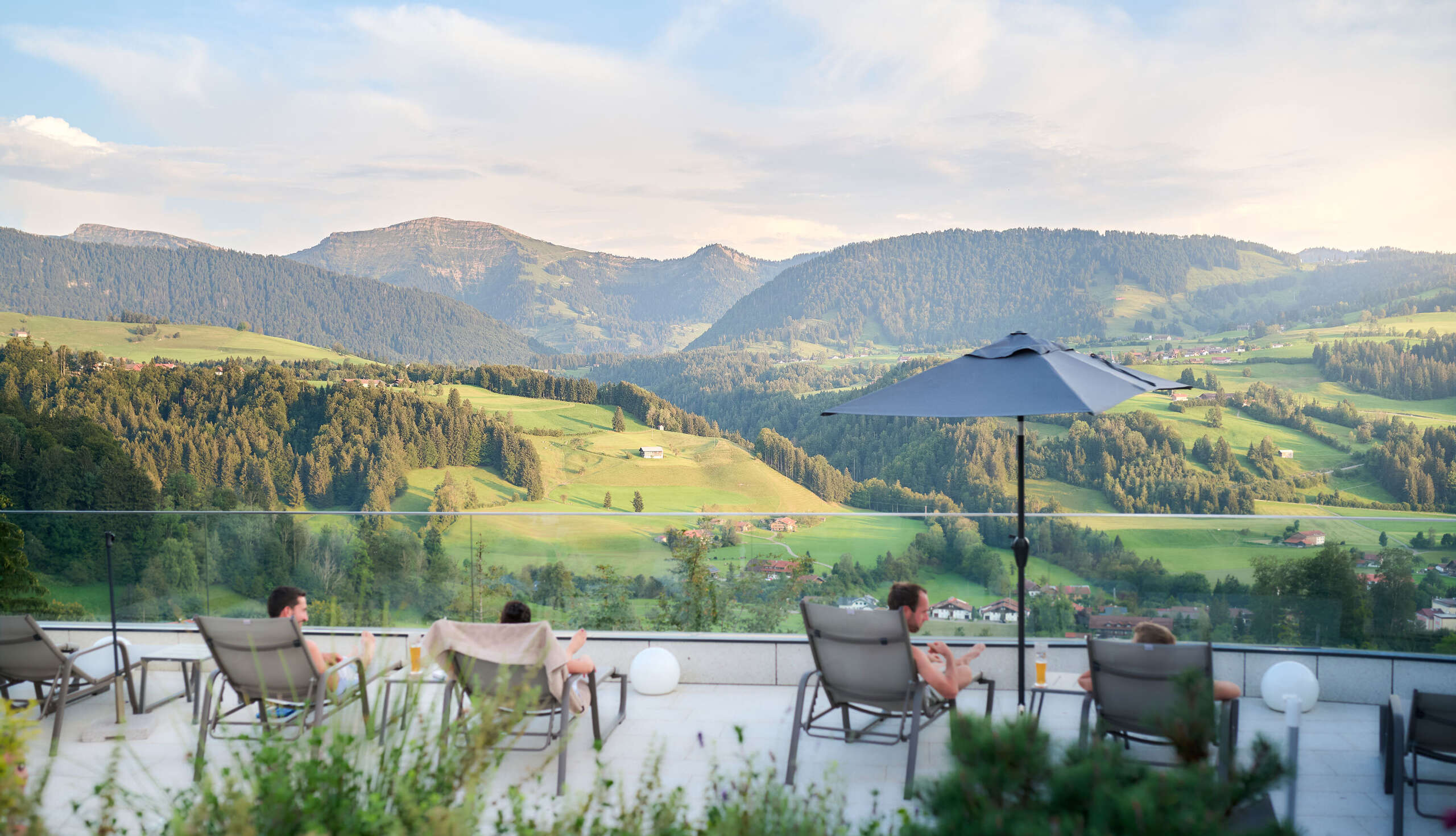Entspannen auf den Liegen der Sonnenterrasse im Aquaria Außensaunabereich mit Bergpanorama im Sommer
